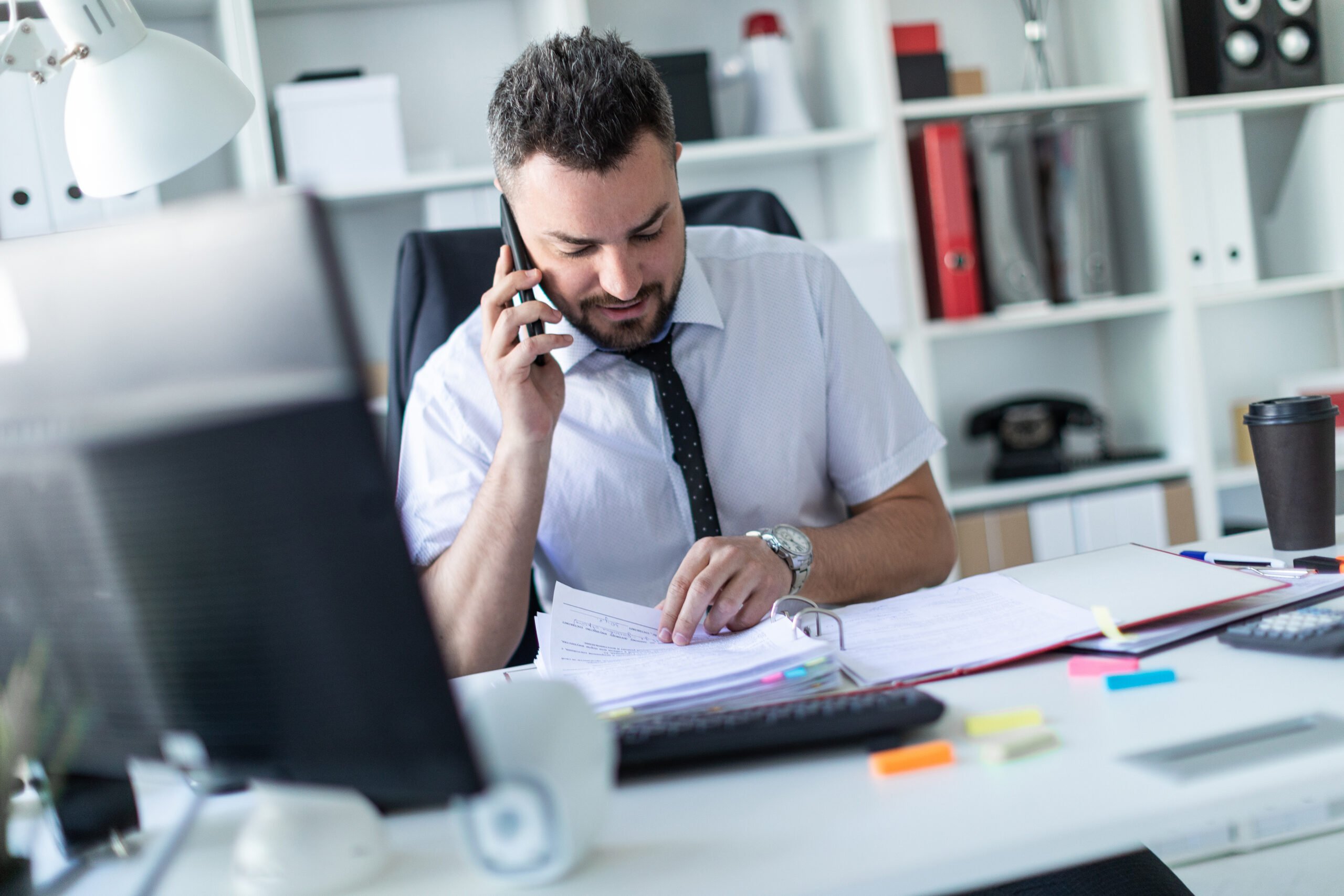 Male executive assistant talking on the phone working with big binder