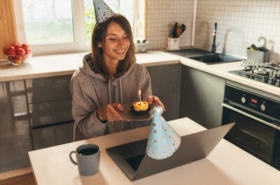 Person smiling and celebrating birthday month in front of computer with meme