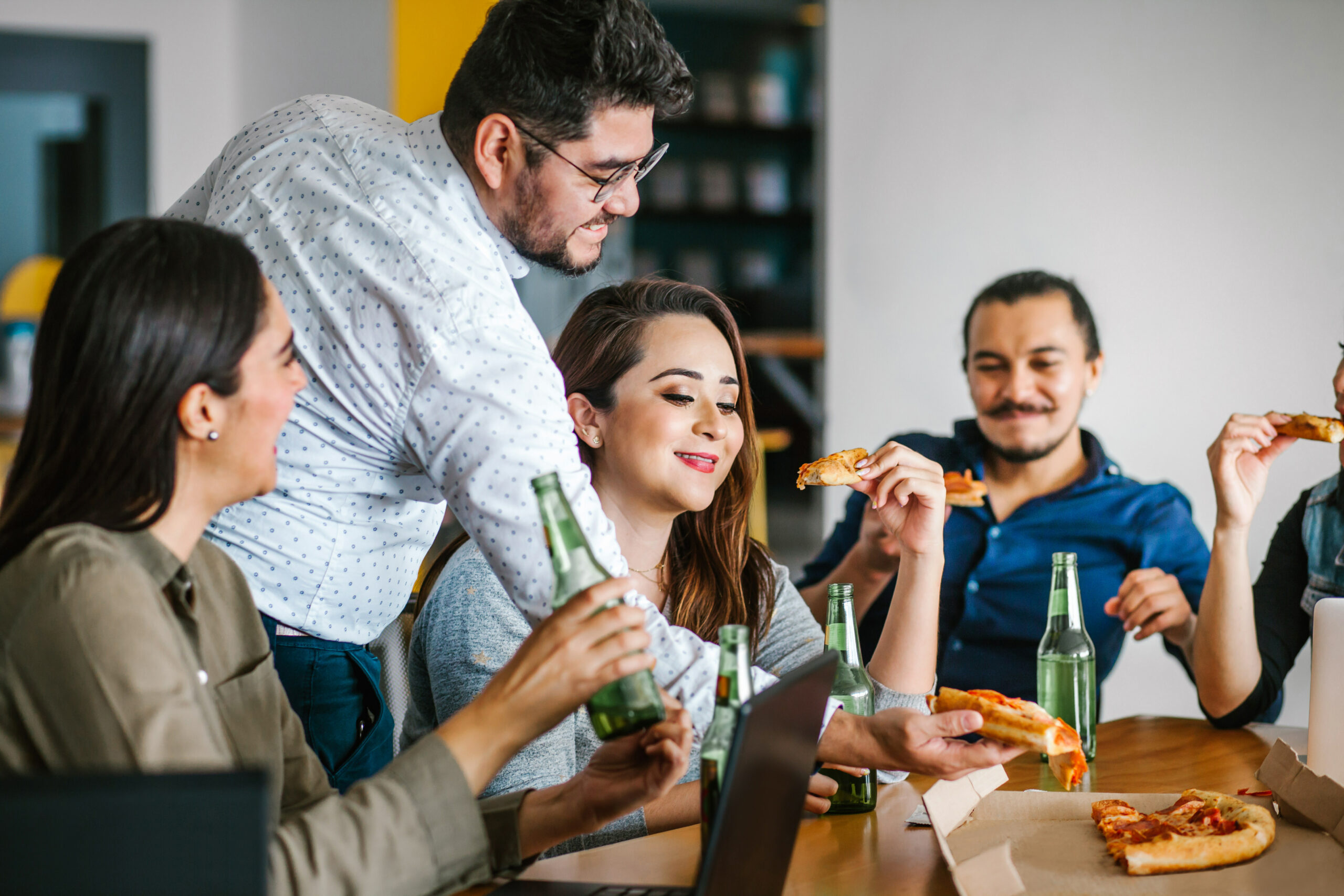 Employees enjoying beverages and pizza at a happy hour for Administrative Professionals Day