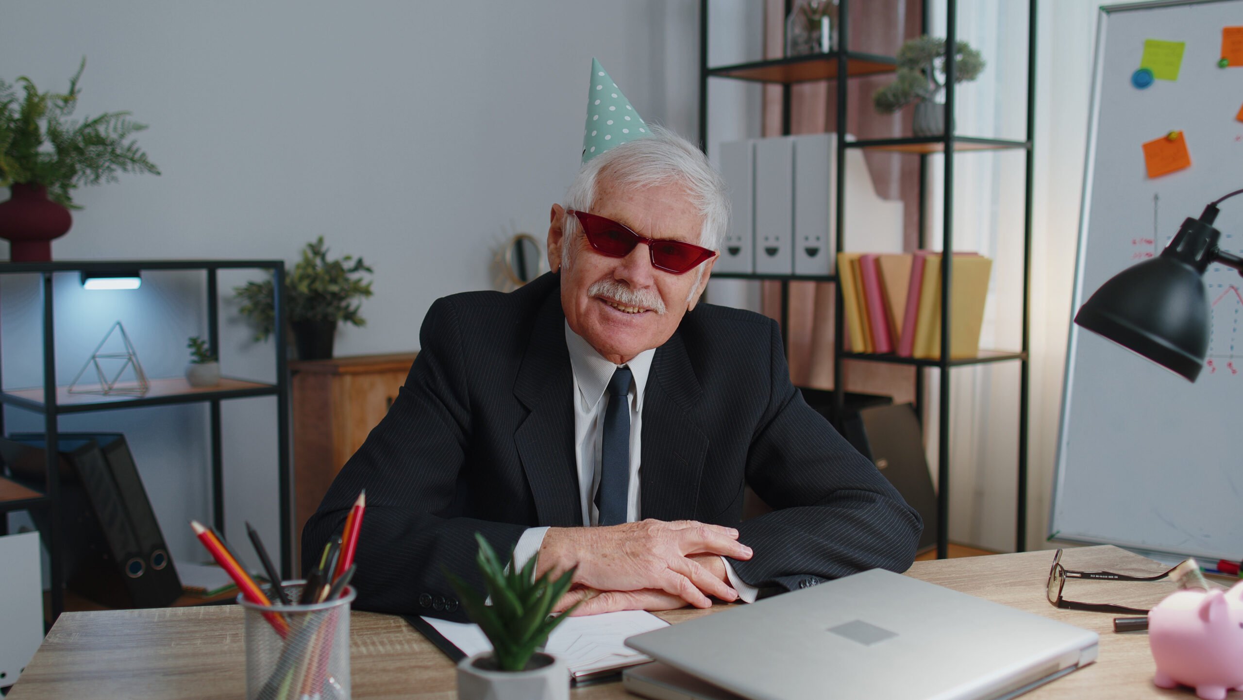Cool CEO in glasses and party hat celebrating office birthday