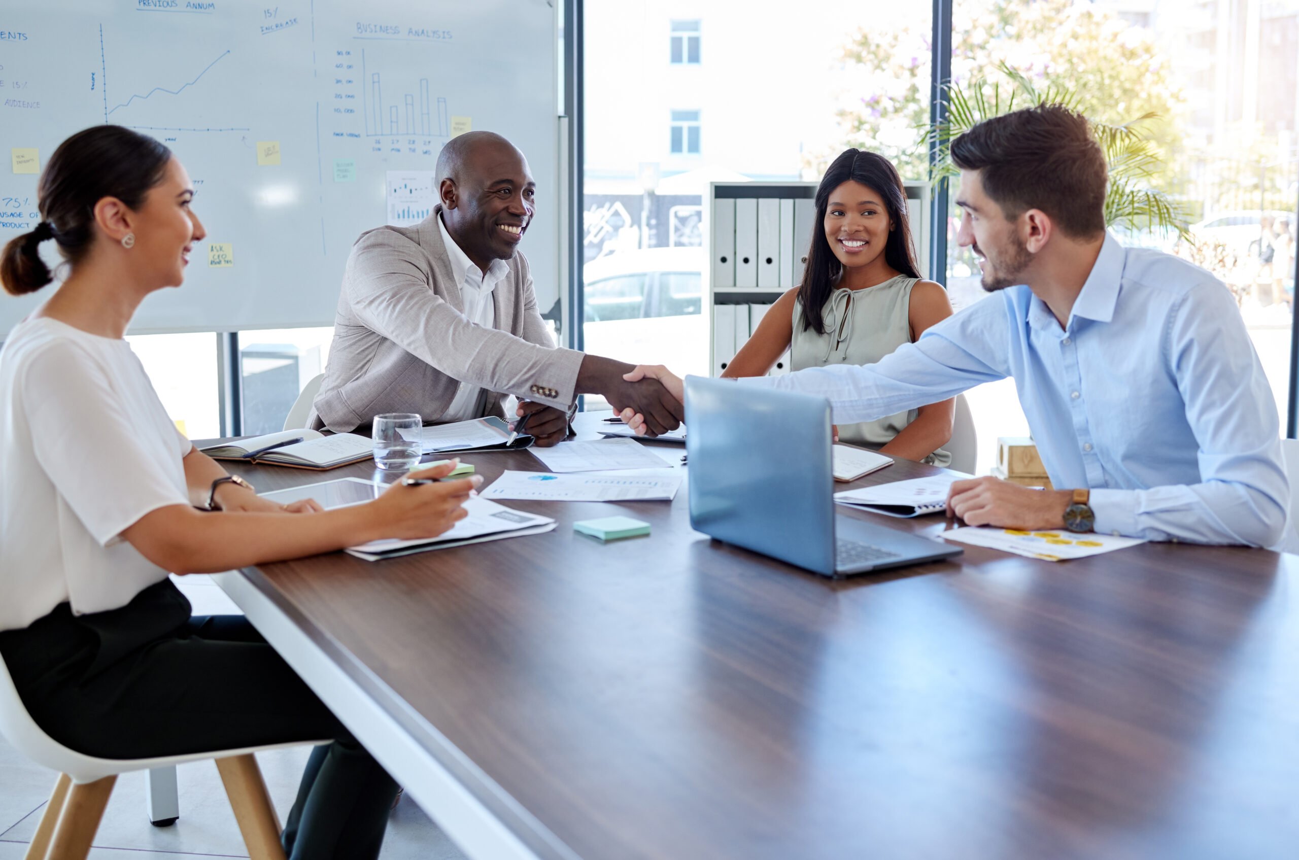 People shaking hands across table at business