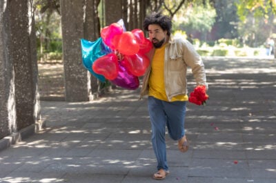 Man running late to birthday with balloons and flowers