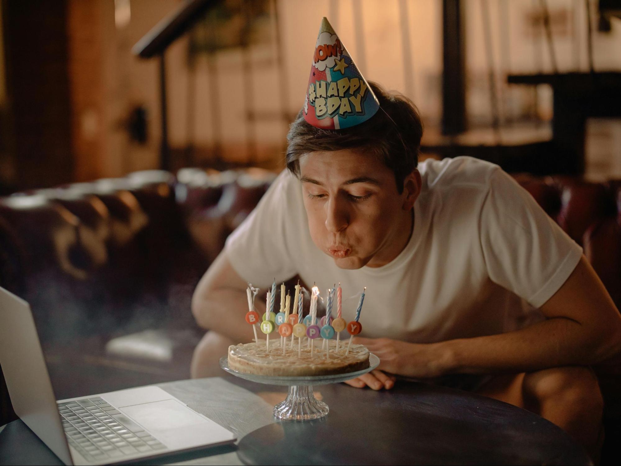 Coworker blowing out candles on cake at virtual birthday party