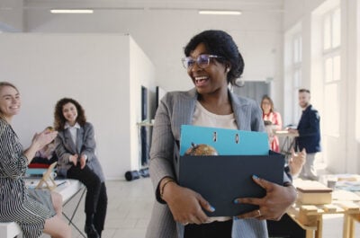 Woman walking into office on first day with employees saying, "welcome to the team"