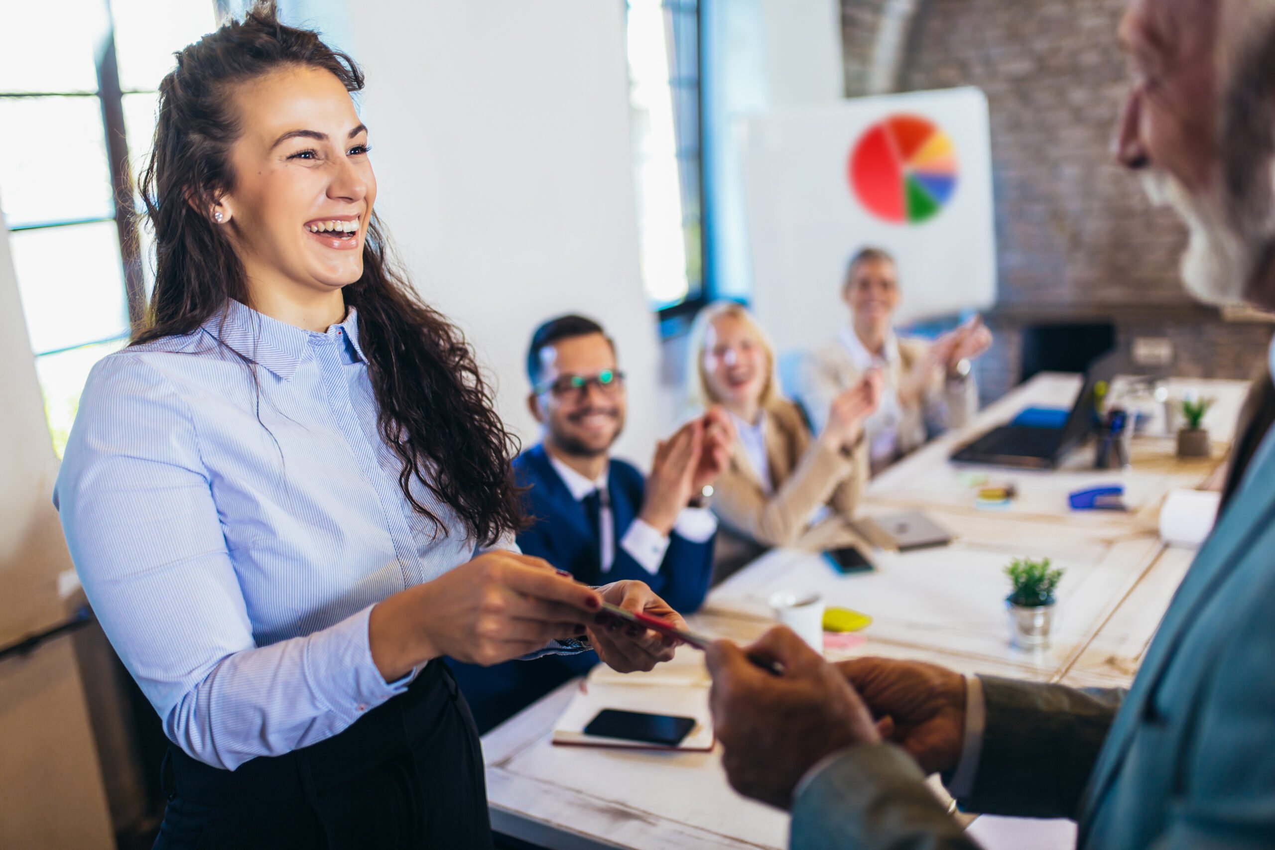 Employee smiling and receiving creative employee recognition award in front of peers