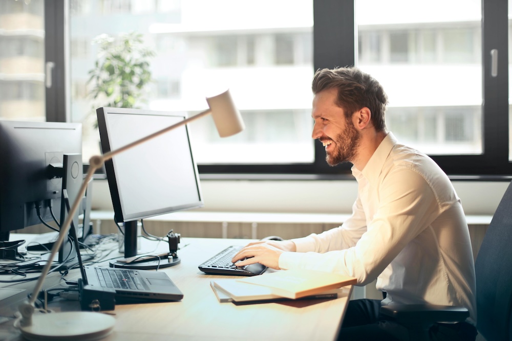 Man laughing in front of his computer, maybe after receiving a virtual greeting card