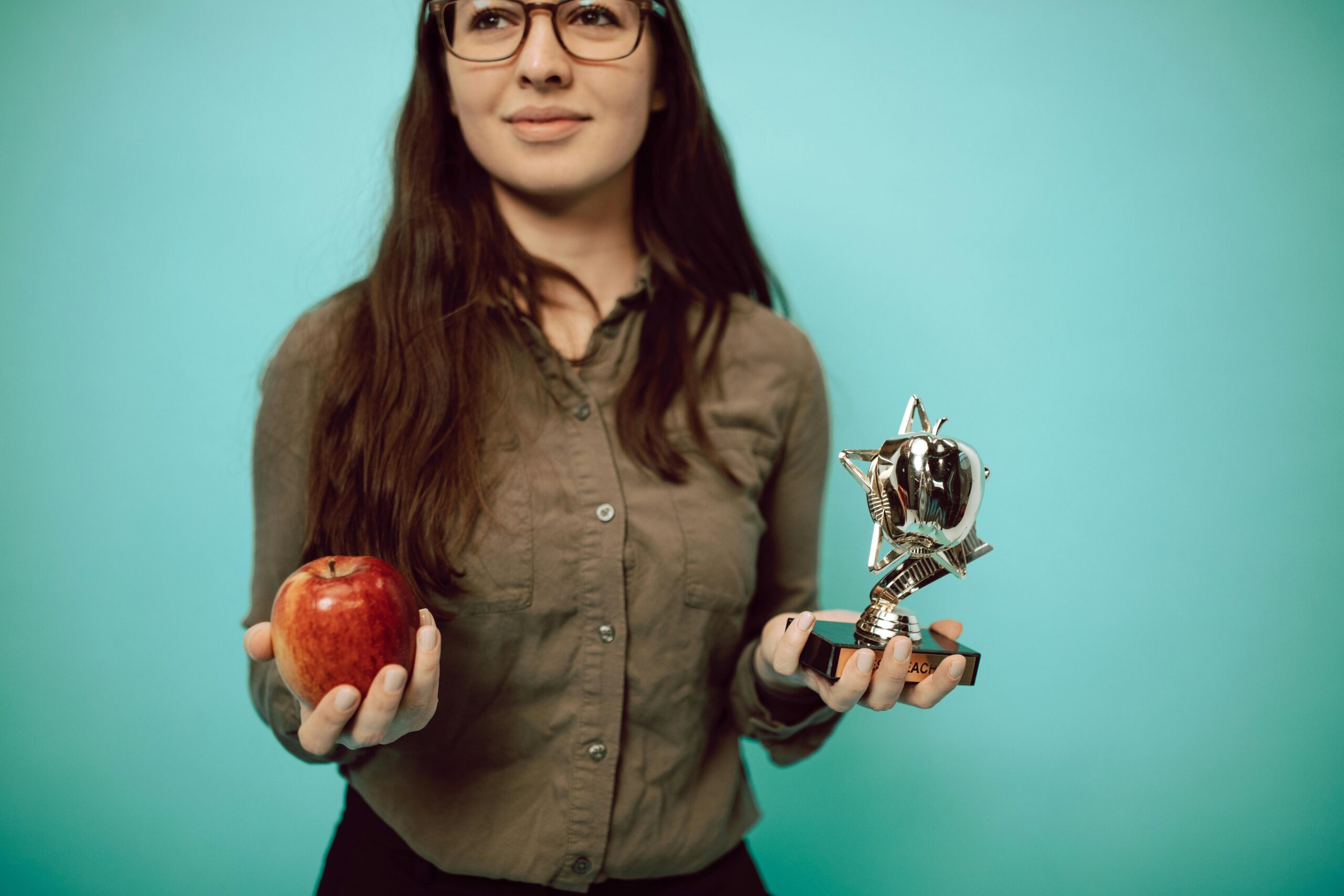 A professional woman holding an apple and an employee recognition trophy