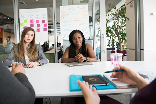 Two engaged employees looking at their peers in a conference room.