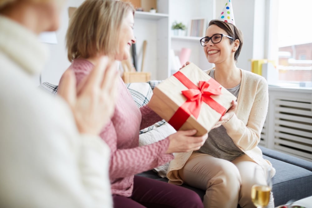 Two women happily exchanging gifts as a thank you message to finds
