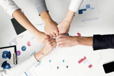Five fists bumping in the middle of a table with graphs and charts on it