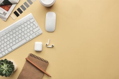Overhead desk short of a keyboard, mouse, airpods, and a notepad