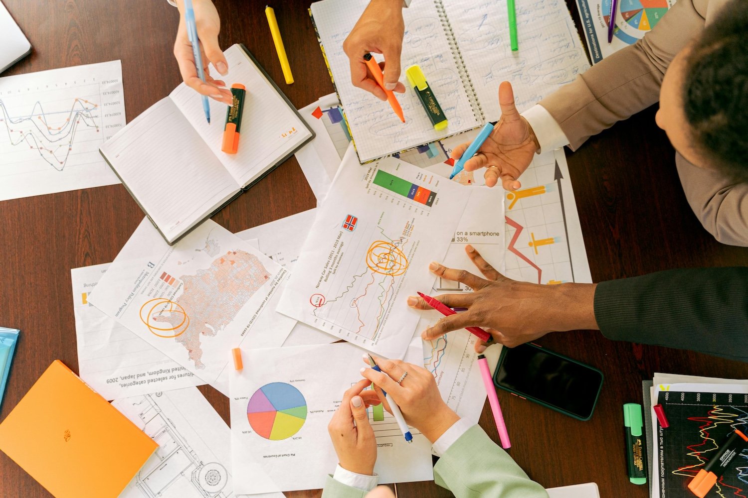 Overhead shot of people designing an employee recognition program with highlighters and charts
