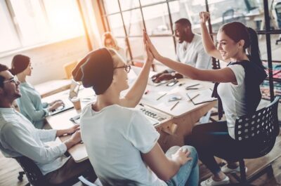 Employee recognition in action with coworkers gathered around a conference table high-fiving
