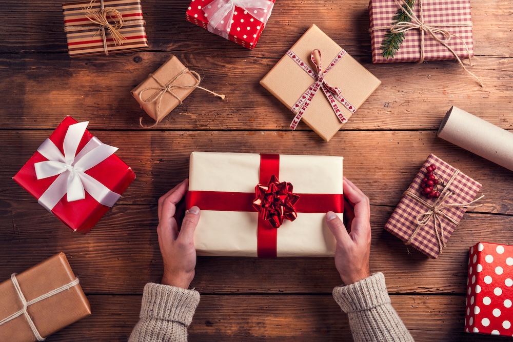 Overhead shot of group gifting and wrapped presents on a wood table