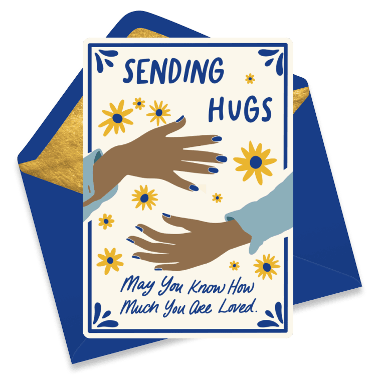 Blue get well card featuring two hands reaching out for a hug with tiny yellow flowers and paired with a dark blue envelope. 