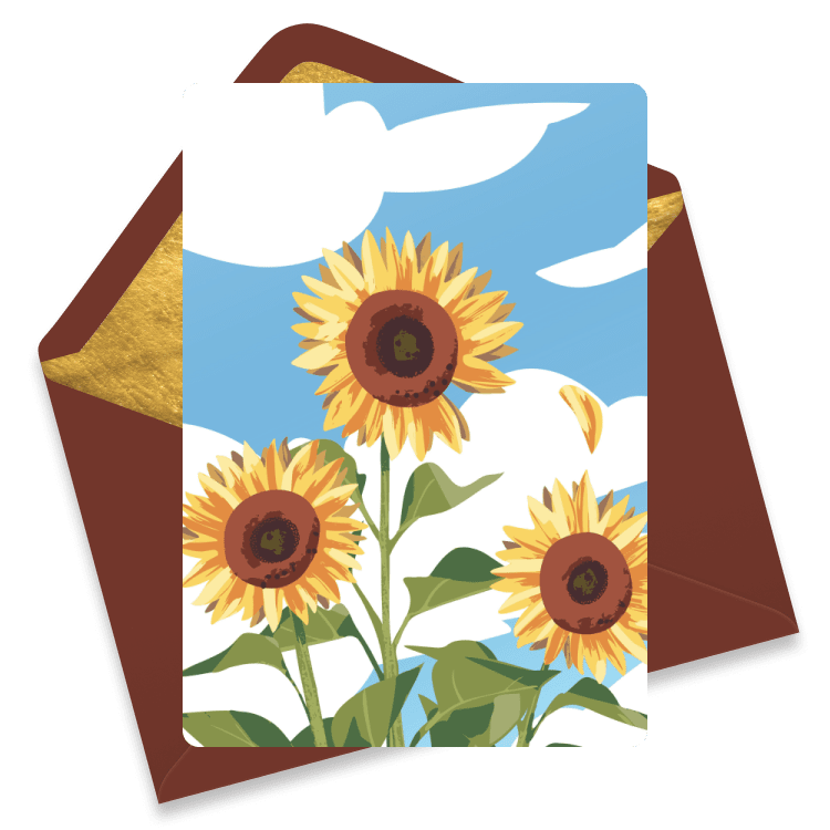 Yellow sunflowers bloom in front of a bright blue sky specked with white clouds