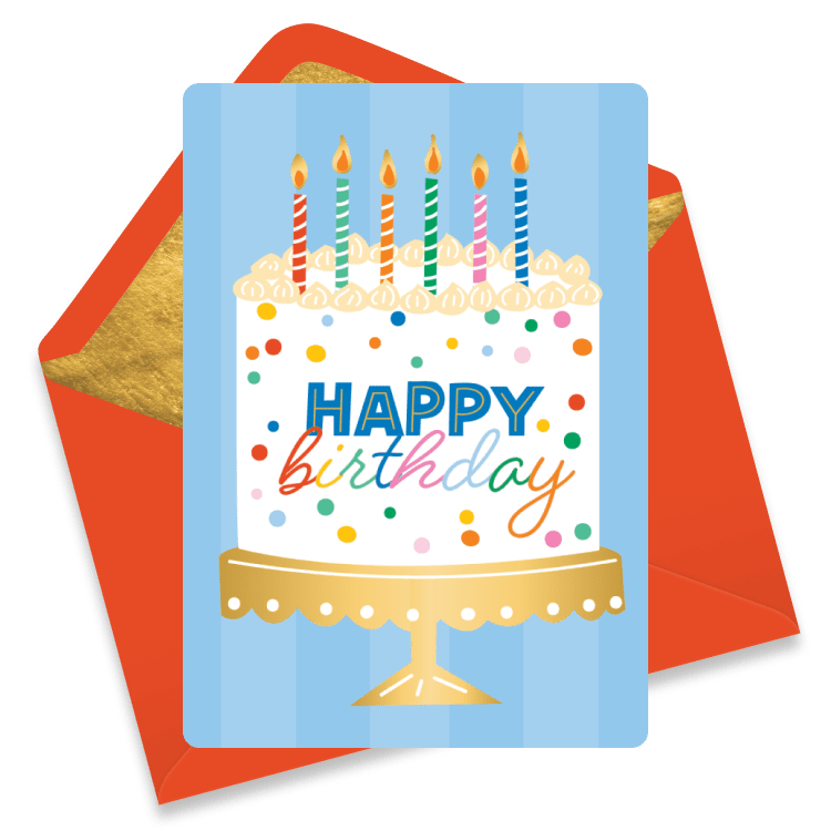 A classic birthday cake on a golden cake stand with rainbow confetti sprinkles and colorful stripes candles on a blue striped background.