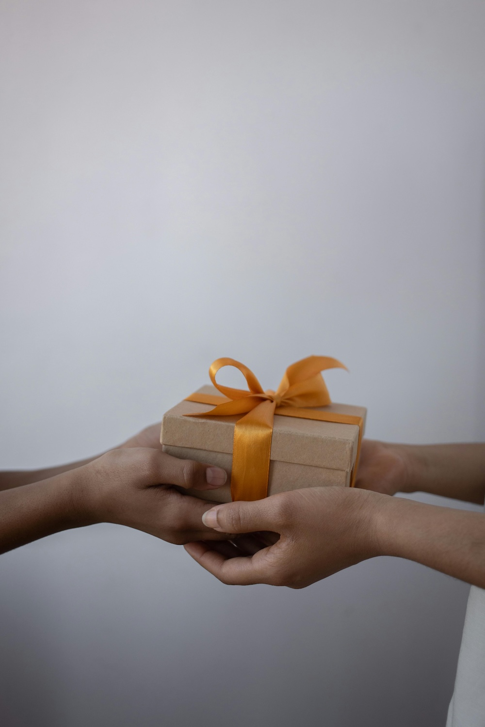Hands exchange a gift for a teacher's birthday.