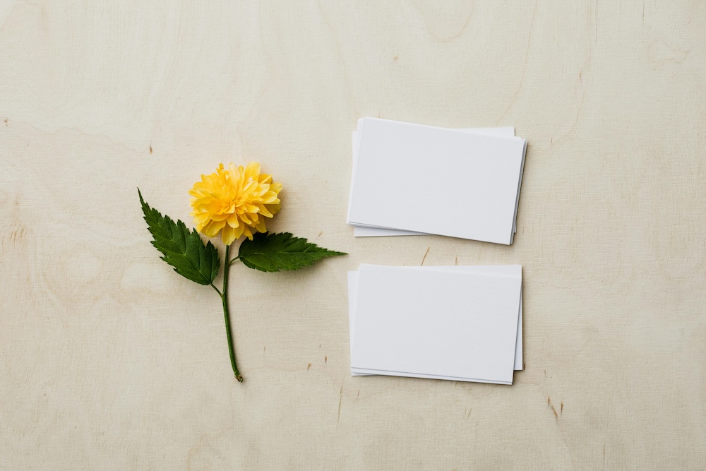 An overhead shot of a yellow flower next to a blank happy work anniversary card