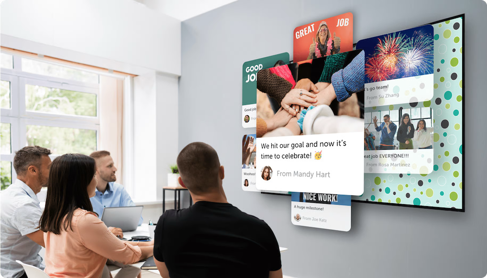A group inside an office looking at a big screen displaying a kudoboard filled with appreciation for employees. Perfect for staff recognition and hospital employee appreciation.