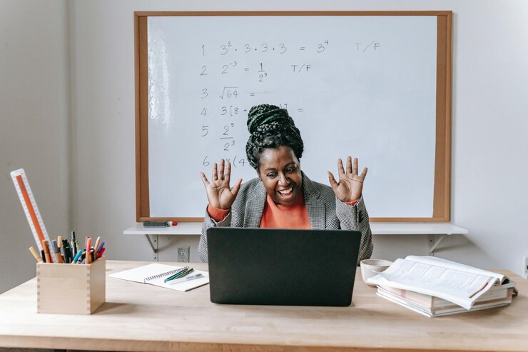 A black teacher smiling and waving at her laptop, receiving an ecard