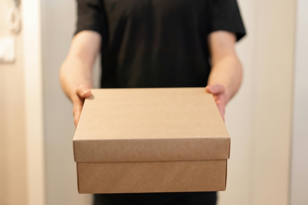 A person holding out a brown box to celebrate a work anniversary