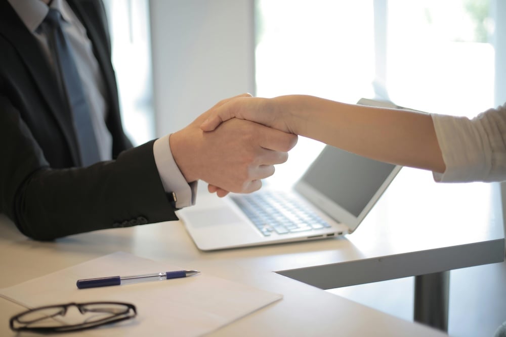 Close-up of hands shaking above a work desk