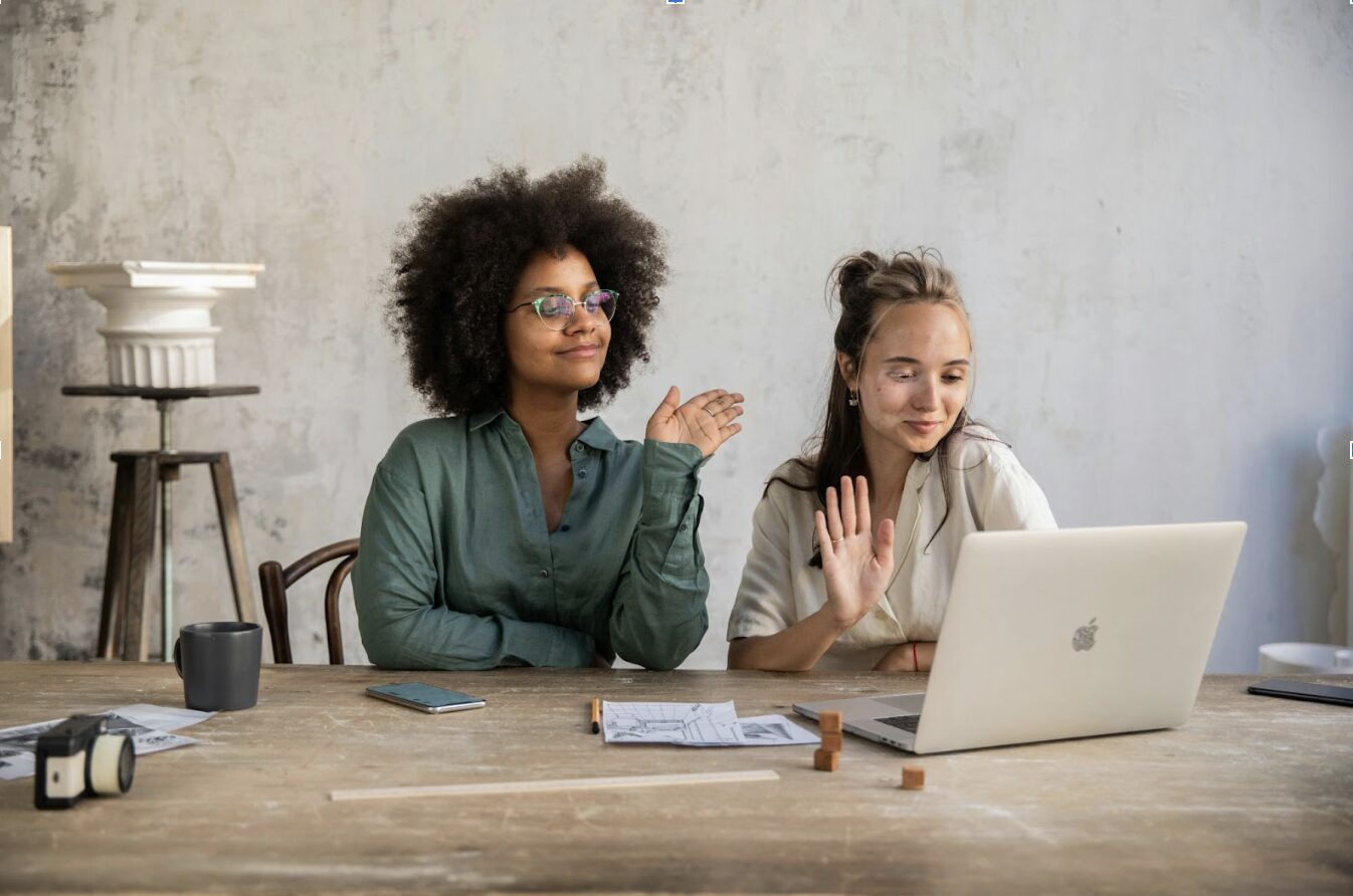 women waving at laptop